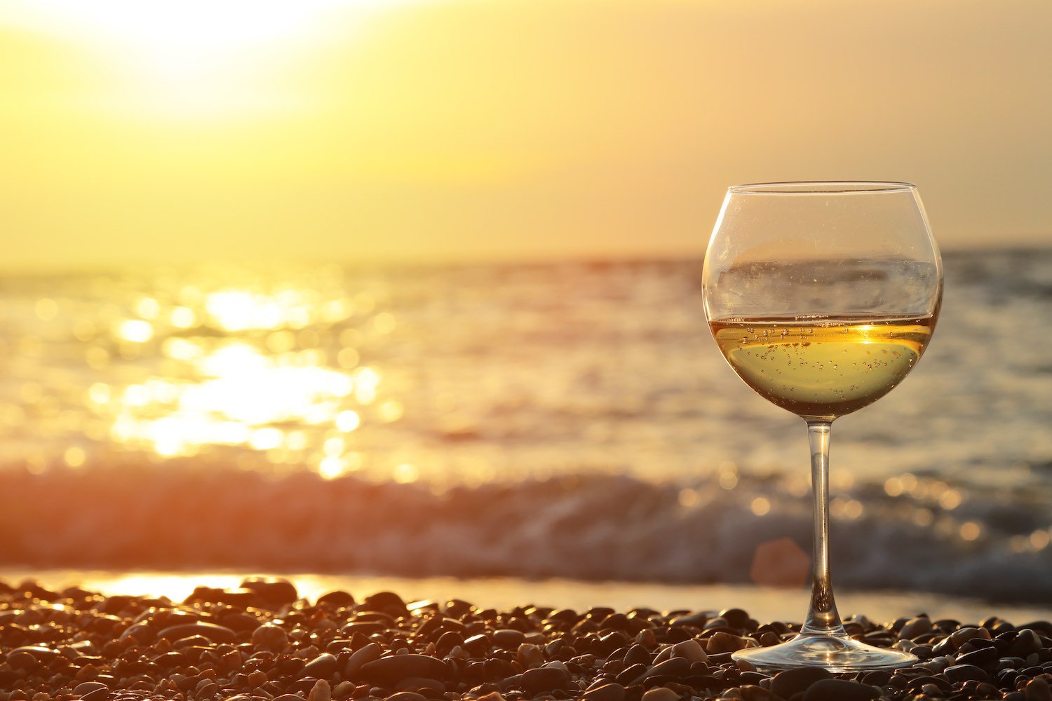 Бокал вина на берегу моря на закате