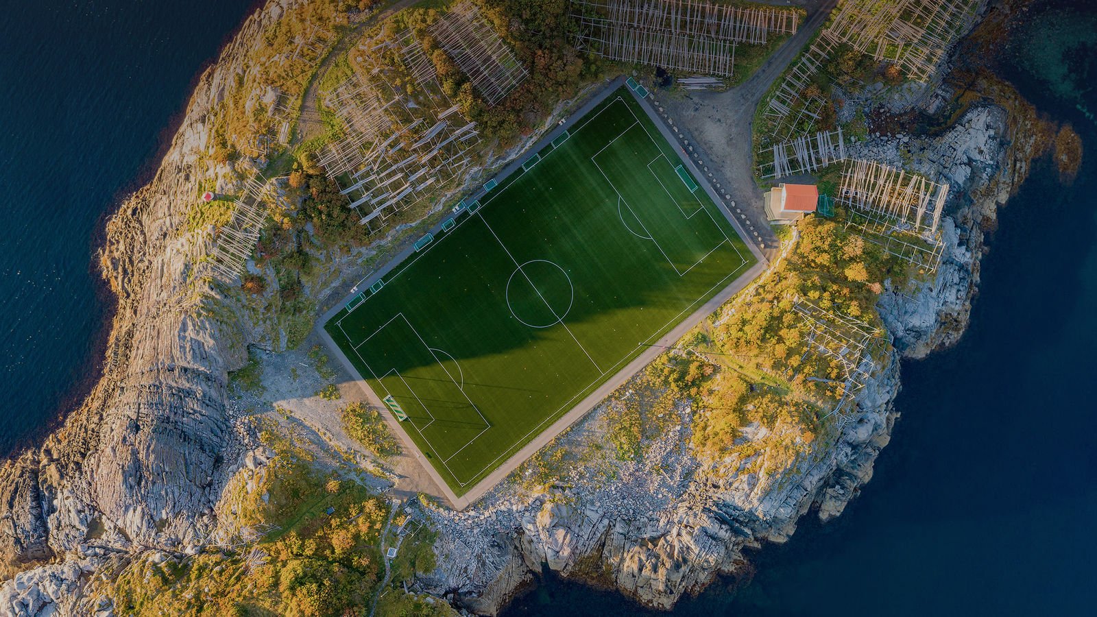 Стадион на острове. Стадион Хеннингсвер, Норвегия. Стадион на острове Хеннингсвер, Норвегия. Стадион на острове Хеннингсвер. Футбольное поле в горах.